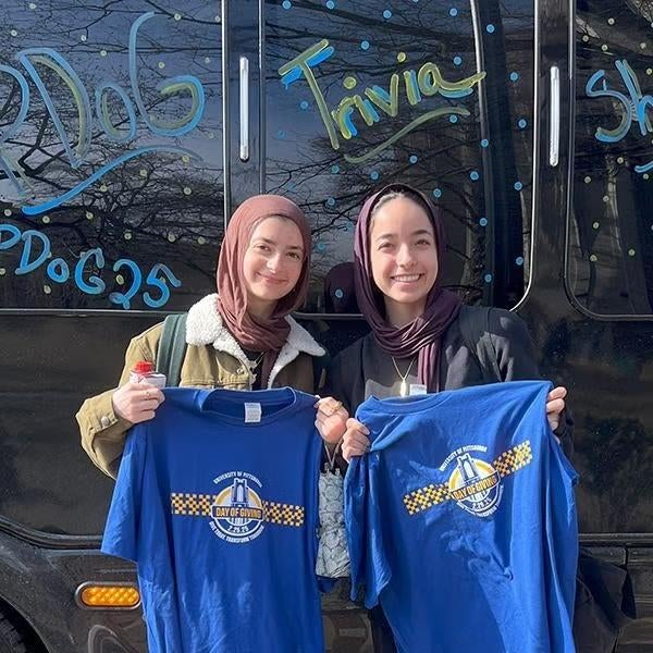 Two students holding up PDOG tshirts