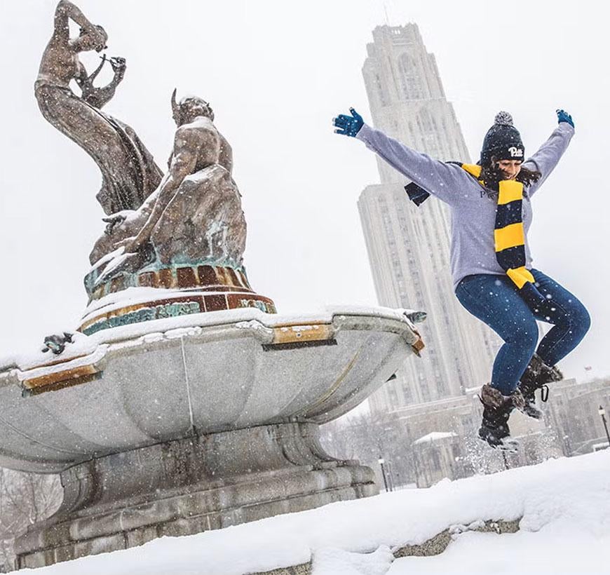 Student jumping from fountain in snow