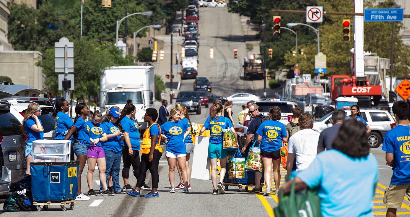 Large group of students in Pitt T-shirts gathered on streets closed to traffic for move-in day on the Pittsburgh campus 
