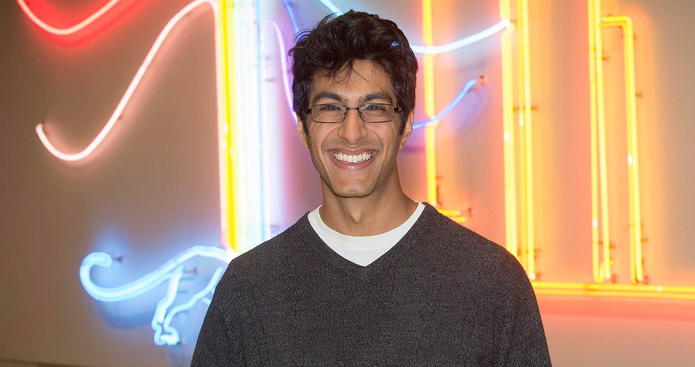 Samir Lakhani standing in front of a colorful neon wall display