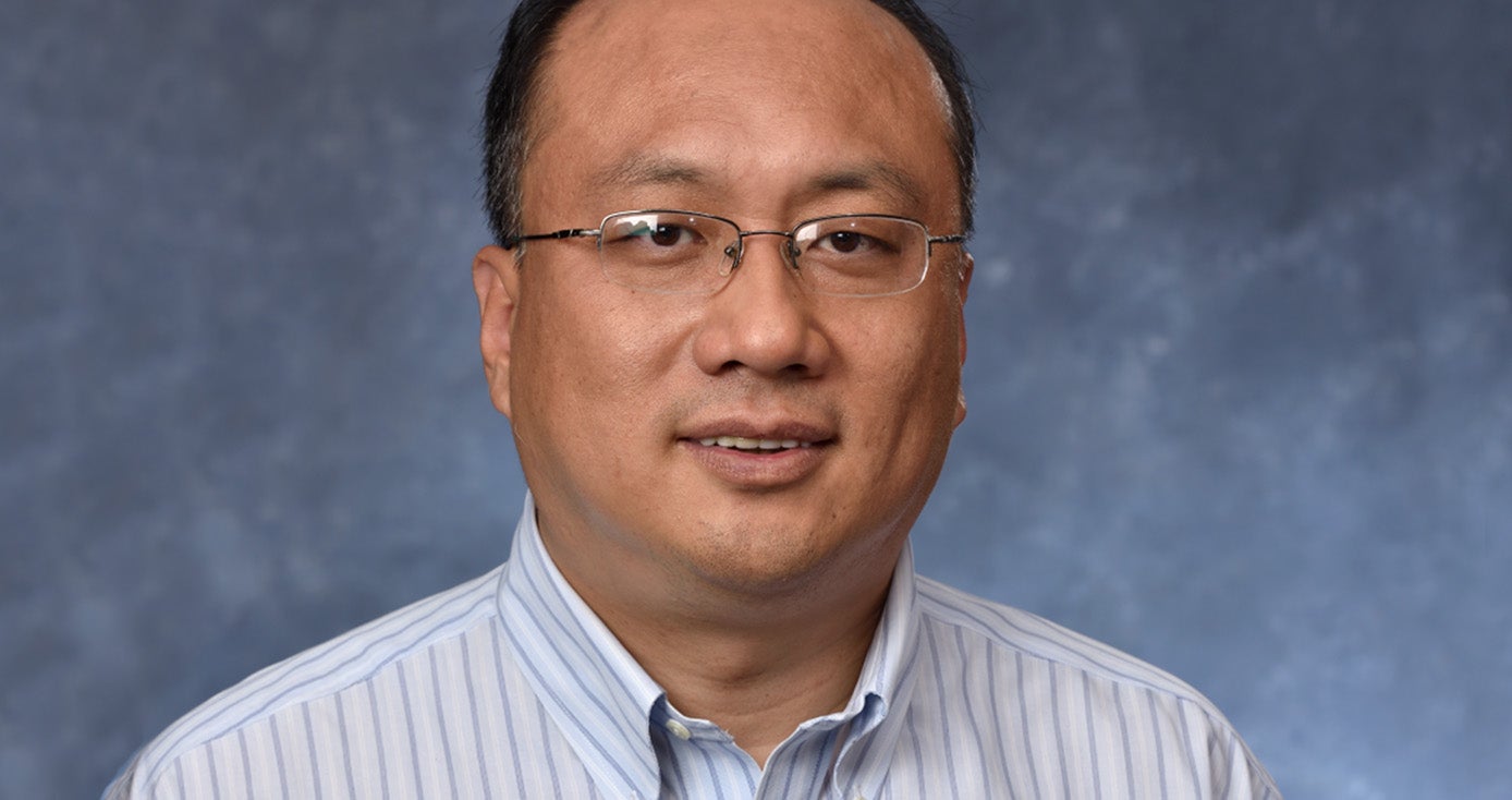 Huang in a collard shirt against a blue background