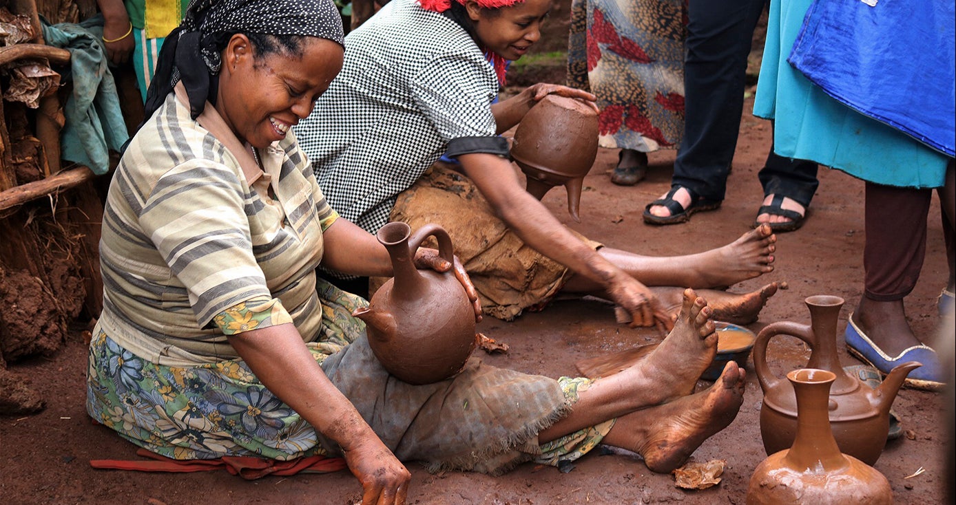 two women sitting on the ground crafting jugs by hand