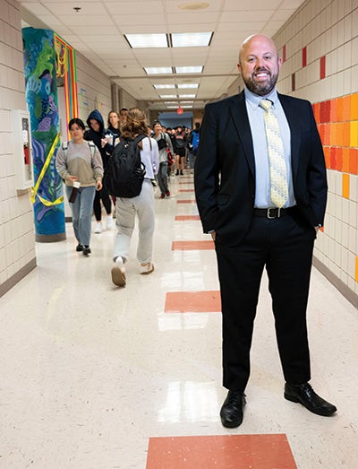 Wagner stands in a school hallway as students walk to class
