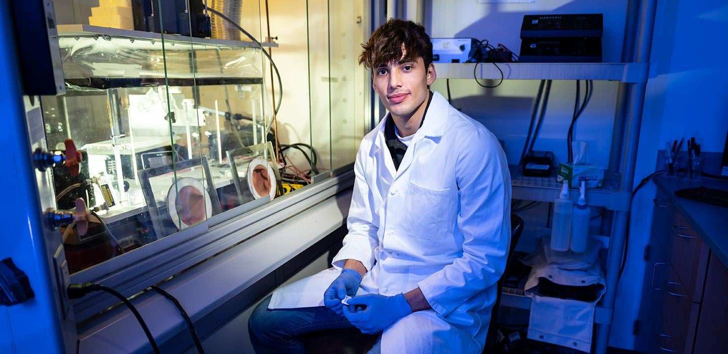 Benjamin Leslie wears a white coat in a lab