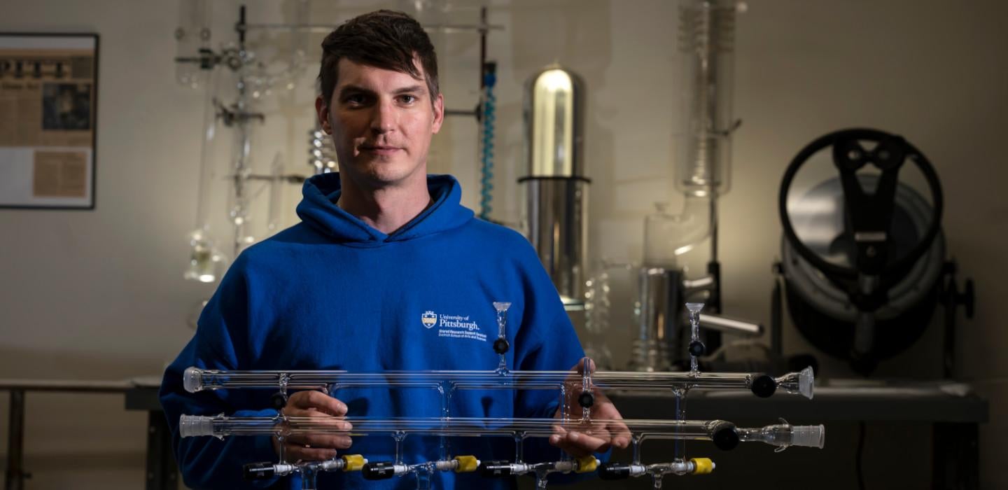 Ryan Tate poses with an apparatus of glass tubing