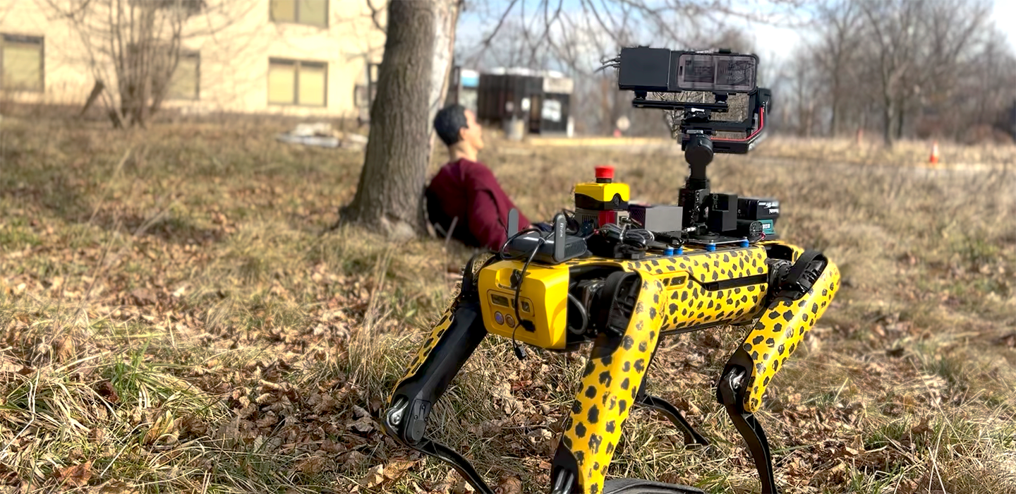 A cheetah-patterned robot outdoors with a test dummy in background