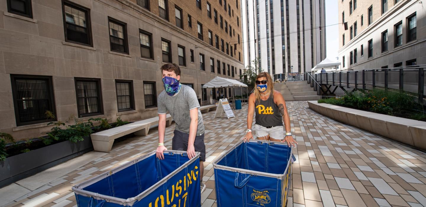 Two students push Pitt carts