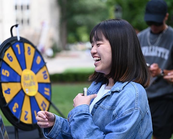 A person laughs as they spin a prize wheel