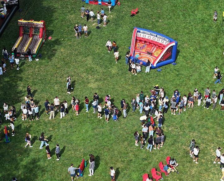 A drone shot of people lined up around inflatable games on Cathedral Lawn