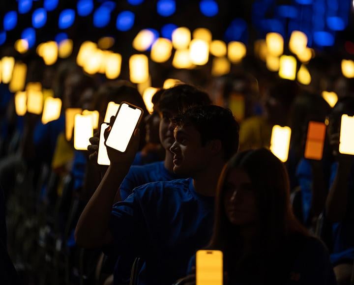 Students hold up yellow and blue screens on their phones