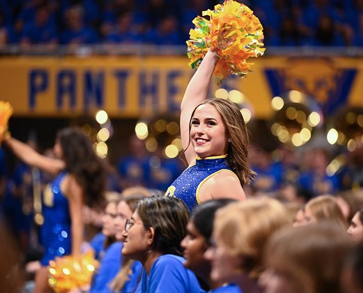 A Pitt cheerleader lifts a pom-pom during a pep rally