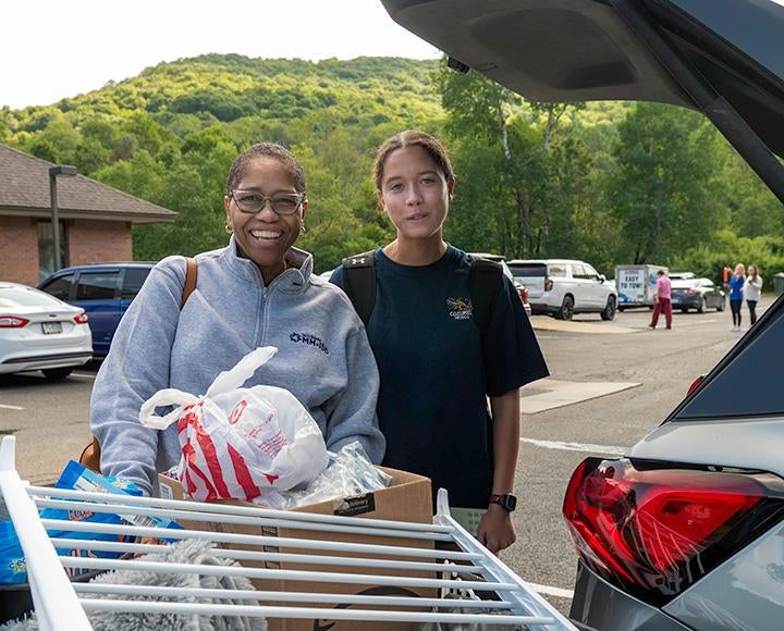 Two people stand by the open truck of a car