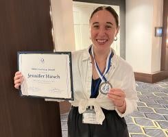 Hirsch holds up her certificate and medal