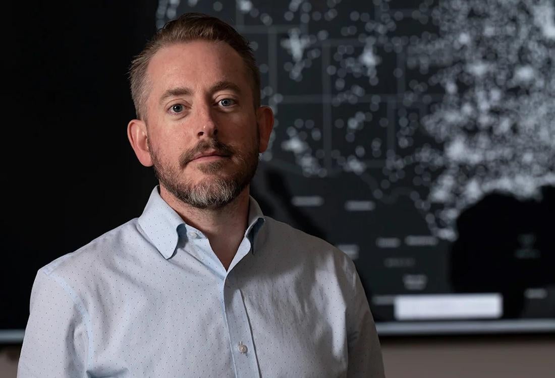 Man standing in front of lighted map of United States.