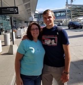 Mother and son posing for the camera with their arms around each other.