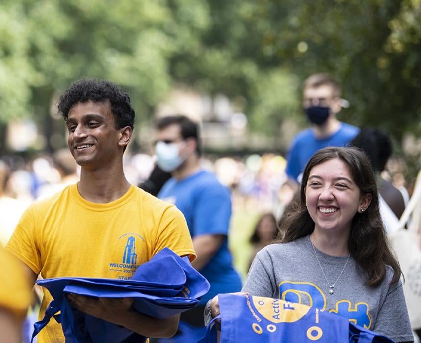 Vijay Cherupally, left, and Kami Olexik, right, pass out reusable shopping bags at the Student Activity Fair