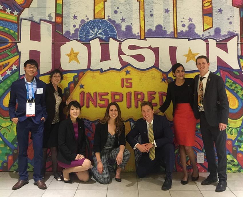 A group of students in suits in front of a mural for Houston, Texas