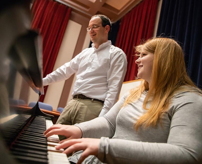 A student plays piano for an instructor