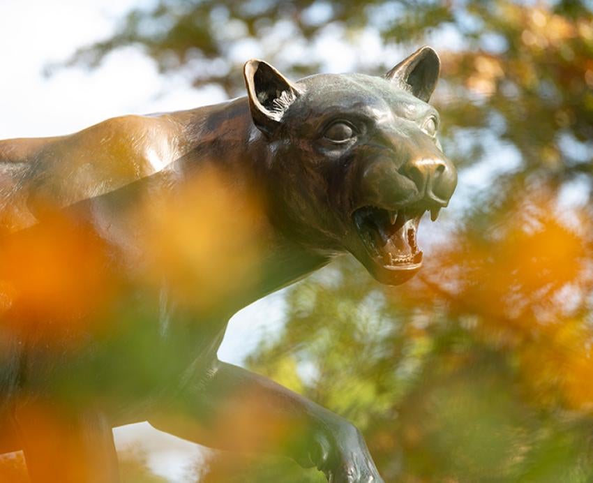 A panther statue behind autumn leaves