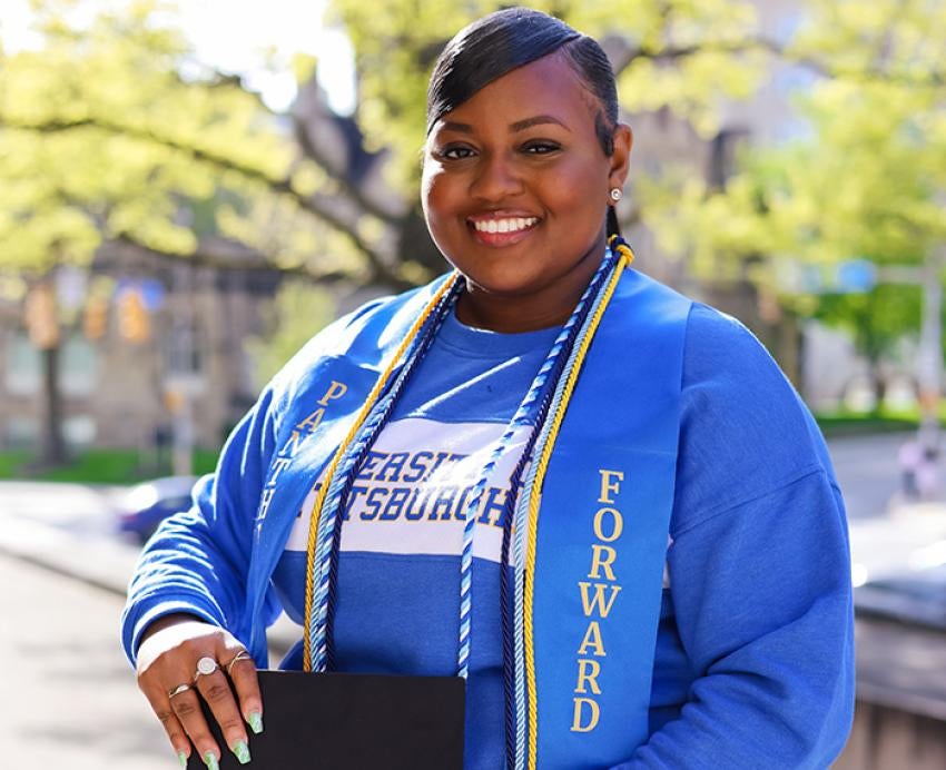 Kayla Kendricks posing with graduation cords and a Panthers Forward stole