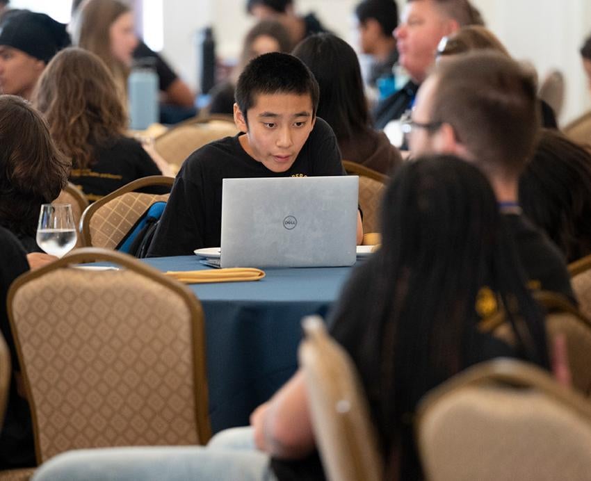 A high school student focuses on their laptop during Pitt's CyberCamp.