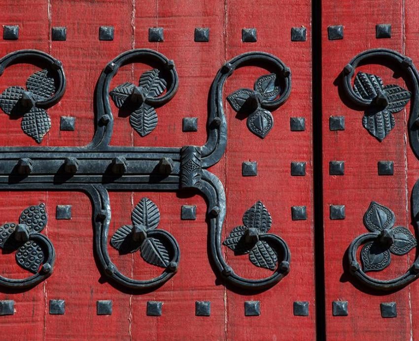 A red door with black wrought iron decoration.
