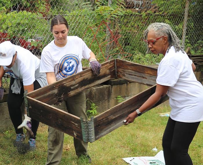 Volunteers lift a garden bed