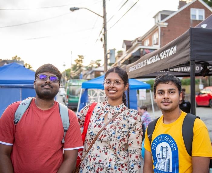 Three people smile and pose for a photo during a Be A Good Neighbor block party.